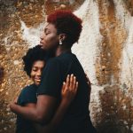 Black mother hugging her child against a wall