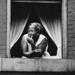 Older Black lady staring out of a window