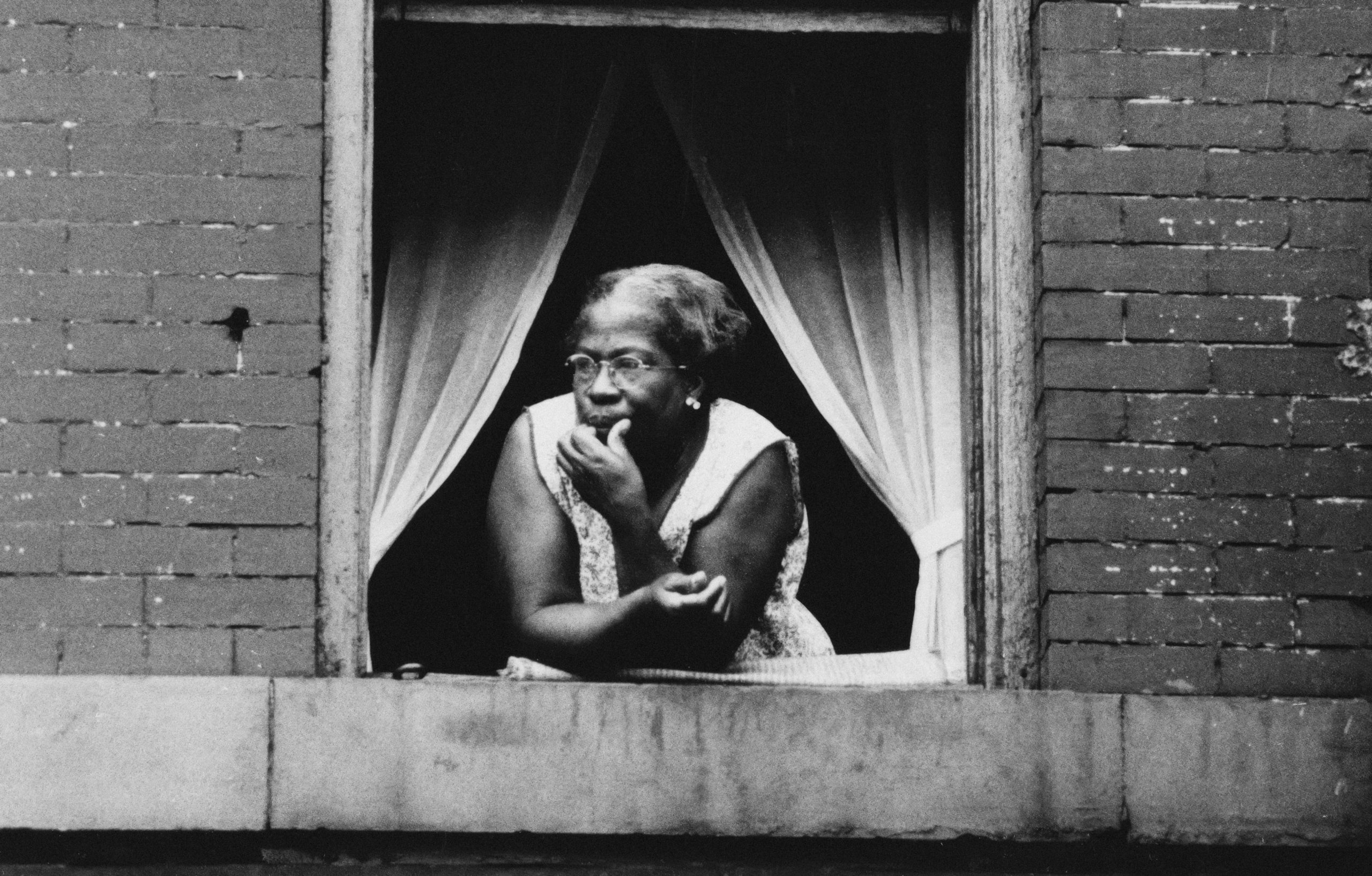 Older Black lady staring out of a window