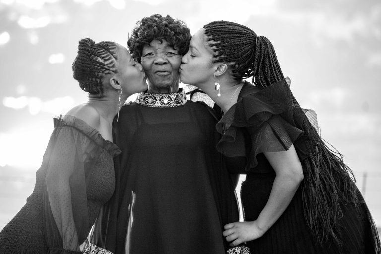 African American elder surrounded lovingly by her daughters